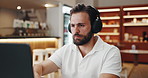 Headphones, reading and man in coffee shop for freelance creative career with online magazine. Audio tech, laptop and male journalist listening to podcast, music or radio in cafe for remote work.