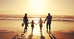 Family, kids and sunset by holding hands at beach of summer vacation, travel trip and bonding together. Back, parents and children walking on ocean for tropical holiday, weekend journey and adventure