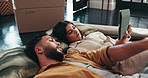 Boxes, tablet and couple on floor, internet and relax in living room with new property. Renovation, planning and man with woman, tech and digital app for real estate, relationship and love in lounge