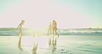 Sunset, people and friends at beach for vacation, travel or freedom for adventure with flare. Outdoor, water or group by ocean for holiday, playful or students kick with energy to celebrate gap year 