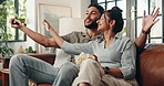 Remote, TV and couple on sofa with popcorn for watching movies, film and series on streaming subscription. Home, happy and playful man with woman for entertainment, bonding or choice in living room