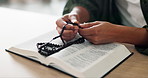 Rosary, hands and man with bible in home for religion study, worship or spiritual journey. Hope, gratitude and male person with scripture for peace, faith or guidance prayer in living room at house.