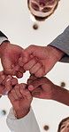 Fist bump, below and hands of business people in office for teamwork, collaboration and partnership. Low angle, corporate diversity and men and women in circle for connection, support and solidarity