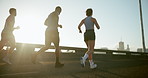 People, group and running on bridge for exercise at sunset with training for marathon, competition or race in city. Athlete, friends and team for workout, challenge or back with fitness on urban road