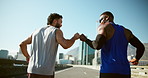 Men, fist bump and running on bridge for fitness with training for marathon, motivation and race in city. Athlete, friends and support for workout, challenge and exercise on urban road in summer