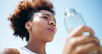 Outdoor, water bottle and woman with fitness, break and relax with blue sky, rest or exercise. African person, athlete or runner in city, hydration or natural detox with workout, below or wellness