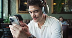 Headphones, relax and man in coffee shop with phone listening to music, radio and playlist. Restaurant, happy and person on smartphone for internet, streaming and audio subscription on break in cafe