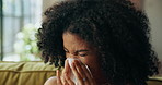 Woman, sneeze and tissue on sofa in home, sick and sinusitis with flu, allergy and rest in living room. African person, cleaning nose and nasal inflammation with cold, mucus or hygiene at apartment