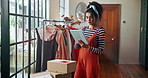Woman, fashion designer and tablet in workshop with clothes, inspection or inventory check at small business. Person, digital touchscreen and app for collection, order or boxes for shipping at studio