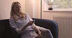 Woman, tv remote and couch to relax home while watching movie, news or reality show for entertainment and media. Female holding television remote control for streaming service in UK apartment