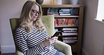 Communication, phone and woman relax on sofa at home, sitting by window with mobile app. Middle aged female alone in living room texting, typing and checking social media smartphone