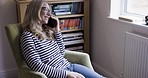 Phone, communication and talking with a mature woman sitting on a sofa in her home alone. Mobile, technology and conversation with a middle aged female chatting while in her house to relax in the day
