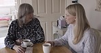 Coffee, communication and mother talking to daughter with love, care and advice in a house. Family, morning and child listening to mother talk during conversation with a drink of tea in the morning