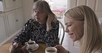 Cat, grandma and woman with coffee in home on table enjoying espresso, cappuccino or caffeine. Pet, tea and old mother and daughter drinking delicious hot beverage, talking or spending time together.