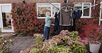 Woman, outside home and hanging up washing doing household chores, cleaning clothing and putting clothes out to dry. Wet laundry, backyard garden and working on domestic house work in UK summer sun 
