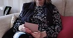 Tablet, online and senior woman on sofa, social media and connect to have conversation, typing and chat. Digital device, mature female and elderly lady browse internet, communicate and in living room