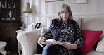 Senior woman, book and reading on sofa to relax in home living room for knowledge with focus. Elderly, lady and books for information, wisdom or religion study on couch, lounge and thinking in house