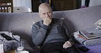 Eating, hungry and rehabilitation with a senior man sitting on a sofa in the living room of his retirement home. Food, snack and recover with an elderly mature male pensioner in his lounge to relax