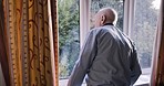 Senior man, window and view in the morning in his retirement home while relaxing in pajamas. Back, behind and retired elderly male looking out of his glass window to relax and think alone