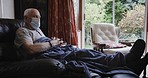 Covid, face mask and senior man on a sofa to relax, recover and heal in isolation in his living room. Sick, covid 19 and elderly guy in retirement resting on the couch in his home for quarantine.