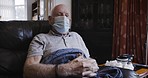 Senior man, covid face mask and home in isolation sick with flu, corona or virus in retirement and old age. Elderly depressed male on sofa during covid 19 lockdown in nursing home for health safety