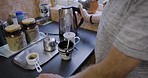 Morning coffee, tea and house kitchen with man hands making breakfast drink with electric pot. Heating drinks on a counter of a person cooking and hand holding a boiler by a table in a household