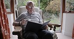Reading, book and senior man drinking coffee while relax in his retirement home for calm peace and knowledge. Novel, education and retired elderly male read a notebook while drinking tea 