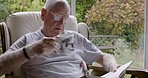 Senior man, reading and coffee relax on sofa in morning or read book for happiness in retirement home. Elderly person, drinking tea and relaxing in couch with notebook in nursing home living room