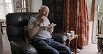 Retirement, old man and eating lunch while sitting in a chair of his retirement home. Nutrition, diet and food or meal with a hungry retired male pensioner eating a plate of healthy consumables