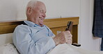 Phone, bedroom and funny with a senior man laughing in the bed of his retirement home alone. Mobile, social media and humor with a mature male lying to relax in his house in the morning with a smile
