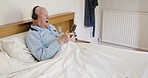 Happy senior man in bed with headphones, phone and singing to music with smile. Nostalgia, technology in retirement and old man listening to online radio streaming service in bedroom of nursing home.
