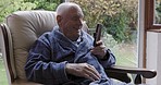 Video call, nursing home and old man in armchair with phone talking with smile living room. Relax, video call and happy conversation for senior man with smartphone, phone call in retirement home.