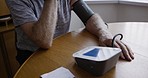 Senior man, blood pressure and home test with medical device to monitor hypertension for healthcare at table for health and wellness. Sick elderly person with heart problem during retirement 