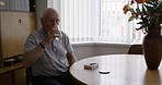 Retirement, healthcare and old man with pills and drink in living room of nursing home or apartment. Medicine, rehabilitation in retirement home and grandpa taking medication for chronic pain at home