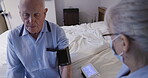 Medical, blood pressure or retirement with a woman nurse and a man patient in the bedroom of a home. Healthcare, exam and assisted living with a senior male having a checkup while sitting on the bed