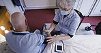 Healthcare, blood pressure and overhead with a woman nurse and a man patient in a retiremen home bedroom. Medical, exam or assisted living with a senior male having a checkup while sitting on the bed