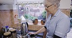Kitchen, caregiver or nurse preparing tea in nursing home or rehabilitation center at breakfast time. Healthcare, support and elderly woman working in senior care making coffee at window on visit.