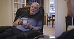 Tea, talking or bonding with a senior man and woman chatting in the lounge of a house. Coffee, conversation and love with a mature couple sitting in the living room of their retirement home together