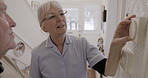 Retirement, thermostat and explain with a woman nurse showing a man patient the temperature dial in his home. Assisted living, heating or switch with a female medicine professional and male resident