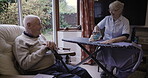 Caregiver, talking and senior man in living room with nurse services, helping and support with laundry. Disability, retirement and nursing homecare of real elderly people on sofa, ironing and happy