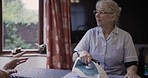 Iron, housework and chatting with a senior couple in the living room of their retirement home together. Laundry, spring cleaning or ironing with a mature man and woman talking and bonding in a house