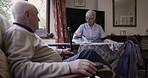 Senior couple, home and rehabilitation with communication and help with laundry and ironing in living room. Old man and woman, caretaker or cleaner together for retirement lifestyle while talking