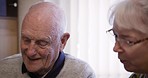 Senior couple, relax and talking in a living room, happy and smile while enjoying a peaceful morning in their home. Love, elderly and old man with woman in lounge, content and satisfied in retirement