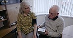 Couple, senior care and blood pressure discussion for health measurement machine in living room. Hypertension, reading and elderly man and woman explain instructions for wife with disability at home