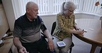 Elderly, couple and hypertension with blood pressure check, retirement and cardiovascular health with old man and woman. Writing notes, medical machine and heart healthcare, cholesterol and diabetes