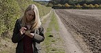 Woman, countryside and smartphone for typing, communication and girl on summer vacation. Female, lady and cellphone with connection, farm and walking outdoor, network for social media and chatting