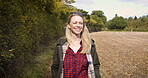 Happy woman, walking and smile for travel, countryside or adventure on a sunny day in the nature outdoors. Blond female smiling in joyful happiness taking a natural walk or stroll outside on a farm