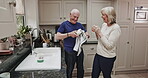 Senior couple, tea and cleaning together in the kitchen standing next to sink having a conversation over coffee. Retirement, elderly husband and wife chat while washing dishes in the morning at home