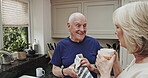Senior couple, tea and cleaning together in the kitchen standing next to sink having a conversation over coffee. Retirement, elderly husband and wife chat while washing dishes in the morning at home