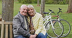 Happy senior couple outdoor and in love, spending quality time together in nature on a bench. Retirement and man and woman enjoy a relax day in a park or garden